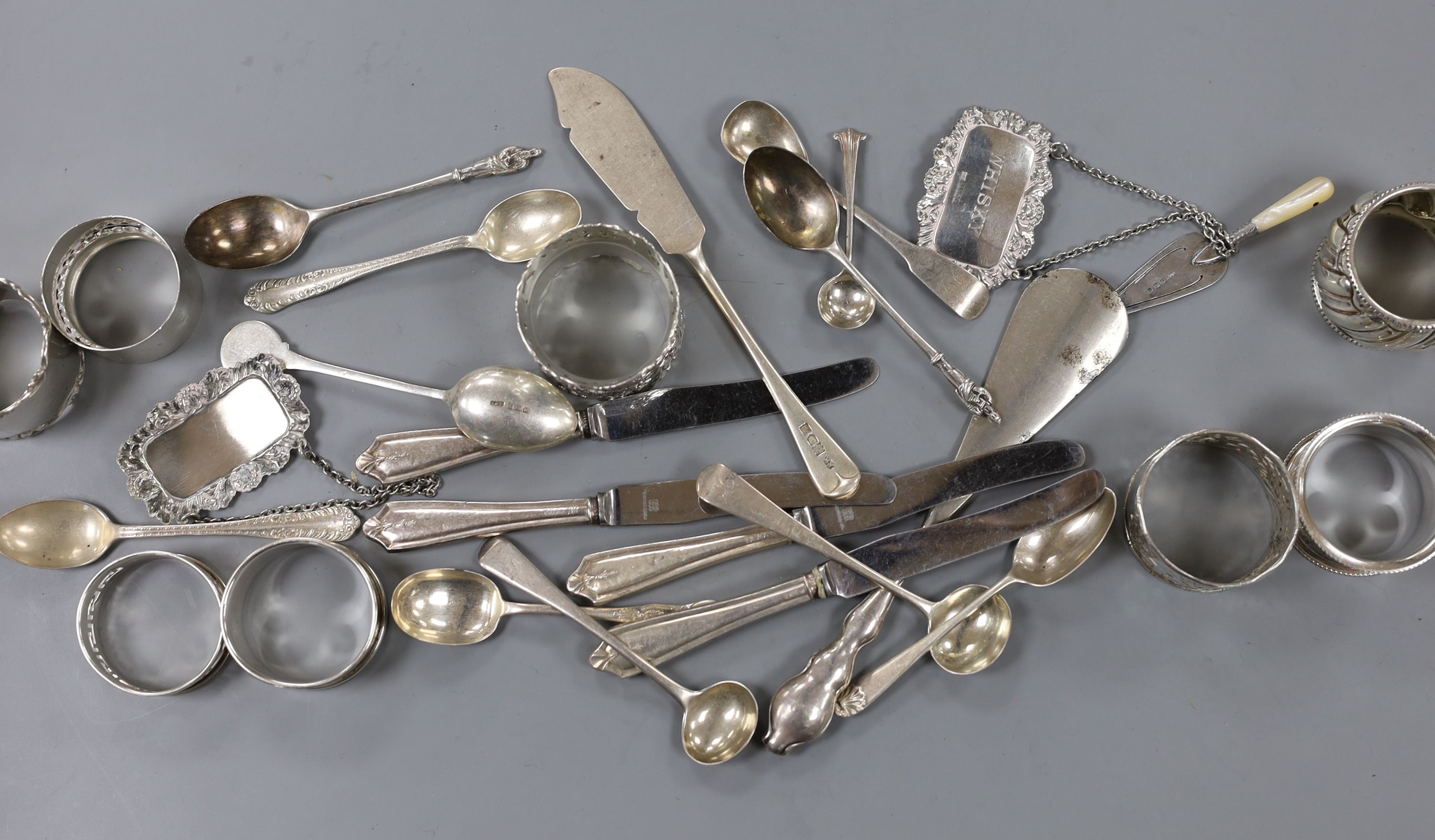 A quantity of small silver cutlery, a pair of silver decanter labels, Sherry and Whisky and eight various silver serviette rings.